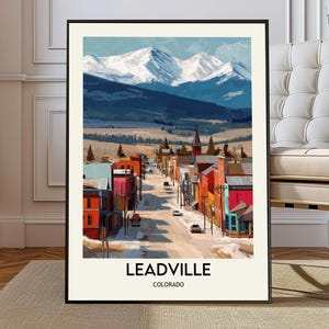 May include: A framed art print of Leadville, Colorado, featuring a street scene with colorful buildings and snow-capped mountains in the background. The artwork has a vintage travel poster style with the town's name at the bottom.