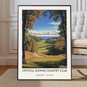 May include: A framed print of Crystal Downs Country Club in Frankfort, Michigan. The artwork depicts a golf course with lush green fairways, trees with autumn foliage, and a view of the water under a blue sky with clouds. The text "Crystal Downs Country Club" is at the bottom.