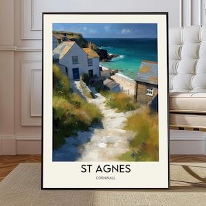 May include: A framed art print of St Agnes, Cornwall. The artwork depicts a coastal scene with white buildings, a path leading to a beach, and turquoise water under a blue sky. The print has a black frame and the text "ST AGNES CORNWALL" at the bottom.