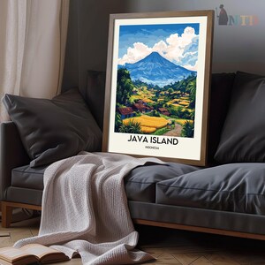 May include: Framed art print featuring a scenic view of Java Island, Indonesia. The artwork depicts a vibrant landscape with a large blue mountain, lush green fields, and small houses. The text "JAVA ISLAND INDONESIA" is displayed at the bottom of the print.