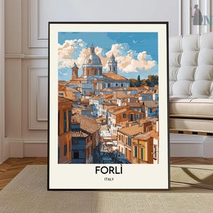 May include: A framed art print featuring a watercolor illustration of Forlì, Italy. The artwork depicts a cityscape with buildings in shades of orange and brown, under a blue sky with fluffy clouds. The word "FORLÌ" is printed at the bottom.