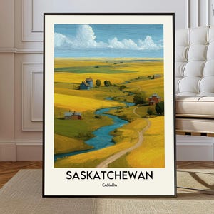 Op de afbeelding: Ingelijste kunstdruk van een landschap met een kronkelende blauwe rivier door gouden velden onder een blauwe lucht met witte wolken. De print bevat de tekst "SASKATCHEWAN CANADA" in zwarte letters.