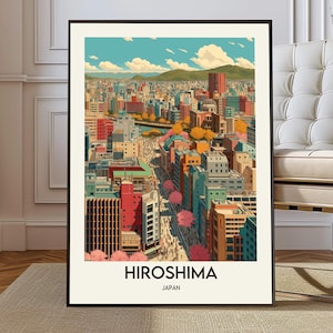 Puede incluir: Una impresión artística enmarcada de Hiroshima, Japón, con un colorido paisaje urbano. La obra de arte muestra edificios de varios colores, un río, montañas y cerezos en flor. El nombre de la ciudad está impreso en negrita, con "Japón" debajo.