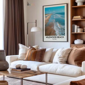 May include: A living room with a white sofa and cushions in brown and cream tones. A framed print of Wildwood Beach, New Jersey, is on the wall. A wooden coffee table and a floor lamp create a comfortable and inviting atmosphere.