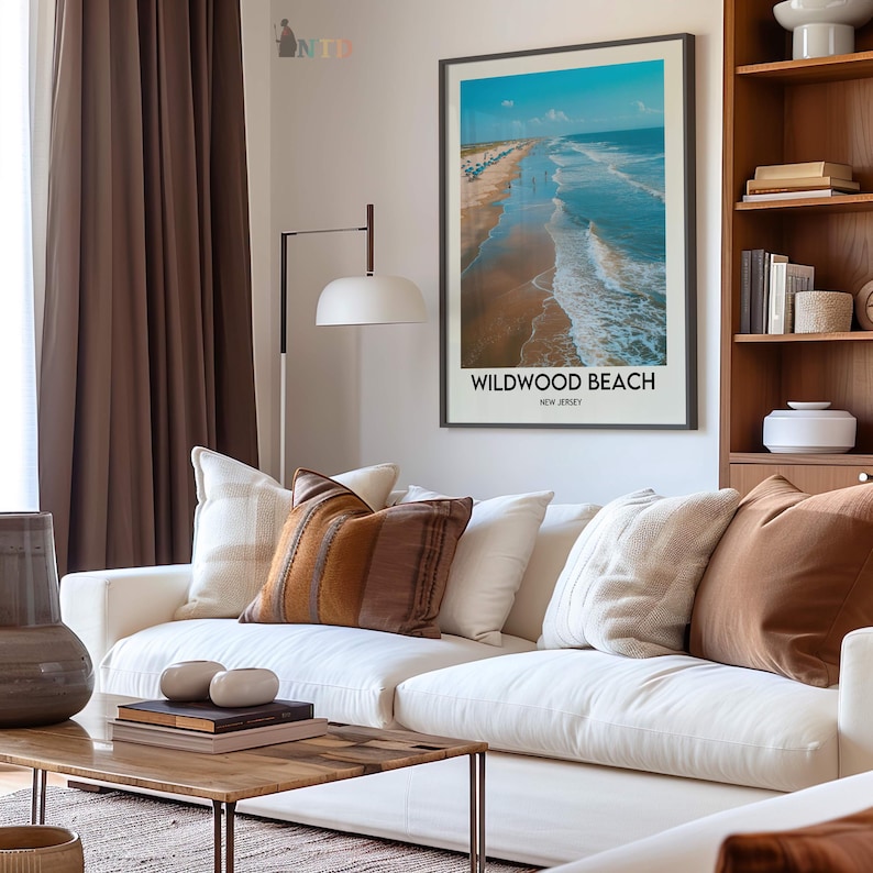 May include: A living room with a white sofa and cushions in brown and cream tones. A framed print of Wildwood Beach, New Jersey, is on the wall. A wooden coffee table and a floor lamp create a comfortable and inviting atmosphere.