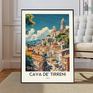 Puede incluir: Una impresión artística enmarcada de Cava de' Tirreni, Italia, con una colorida ilustración de un pueblo en la ladera con edificios, árboles y un cielo azul. La impresión tiene un borde blanco y el texto "CAVA DE' TIRRENI ITALY" en la parte inferior.