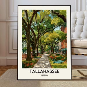 May include: A framed art print featuring a stylized illustration of a tree-lined street in Tallahassee, Florida. The artwork showcases a pathway, buildings, and vibrant flowers. The text "TALLAHASSEE FLORIDA" is displayed at the bottom.