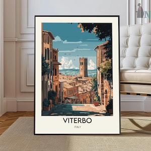May include: A framed art print featuring a stylized illustration of Viterbo, Italy. The artwork depicts a cobblestone street leading towards a tall tower, with buildings in shades of orange and brown. The sky is blue with white clouds. The word "VITERBO ITALY" is printed at the bottom.