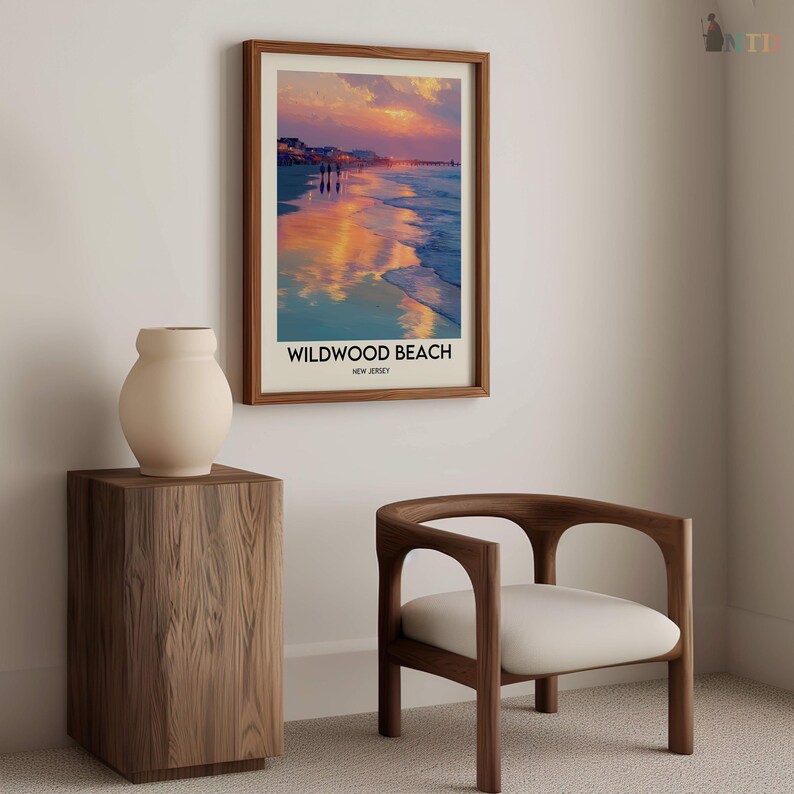 K&ouml;nnte beinhalten: Ein gerahmtes Wildwood Beach-Poster mit einer Sonnenuntergangsszene, das &uuml;ber einem h&ouml;lzernen Beistelltisch mit einer cremefarbenen Vase und einem Holzstuhl mit einem wei&szlig;en Kissen ausgestellt ist. Das Poster hat einen braunen Rahmen.