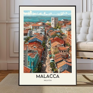 Può includere: Una stampa artistica incorniciata di Malacca, Malesia, con un'illustrazione dettagliata di una scena di strada cittadina. L'opera presenta edifici colorati con tetti di tegole rosse, una torre bianca e il mare blu sullo sfondo. La parola "MALACCA" è stampata in basso.