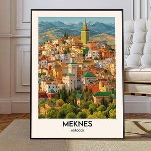 Puede incluir: Una impresión artística enmarcada de Meknes, Marruecos. La obra de arte representa un paisaje urbano vibrante con edificios coloridos, un prominente minarete verde y un telón de fondo de colinas y montañas. El texto "MEKNES MARRUECOS" se muestra en la parte inferior.