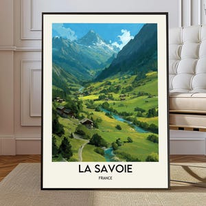 May include: A framed vertical wall art print featuring a painted landscape of the Savoie region in France. The image depicts a snow-capped mountain peak, a lush green valley, a winding blue river, and small houses. The text reads LA SAVOIE FRANCE.