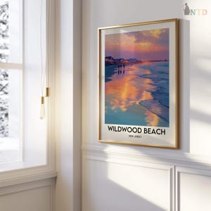 K&ouml;nnte beinhalten: Ein gerahmter Druck von Wildwood Beach, New Jersey, mit einem Sonnenuntergang &uuml;ber dem Meer. Das Kunstwerk hat einen goldenen Rahmen und zeigt Strand, Pier und Himmel in Orange-, Rosa- und Blaut&ouml;nen. Der Text "Wildwood Beach, New Jersey" befindet sich unten.
