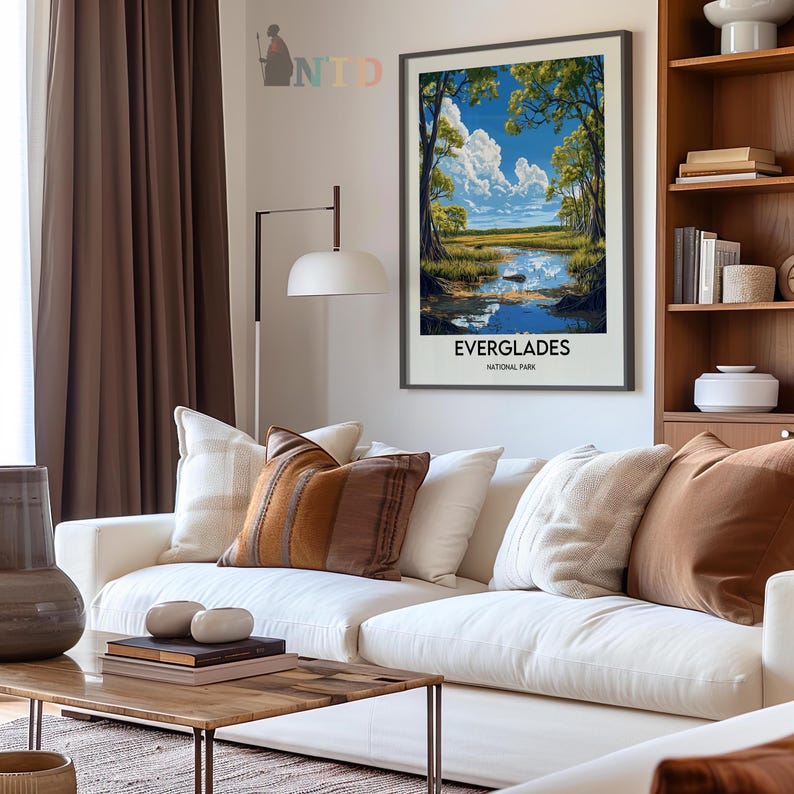 Op de afbeelding: Een vintage poster met een schilderachtig uitzicht op het Everglades National Park. De poster toont een blauwe lucht met witte wolken, groene bomen en een kalm wateroppervlak dat de lucht weerspiegelt. De tekst "EVERGLADES NATIONAL PARK" is onderaan de poster gedrukt.