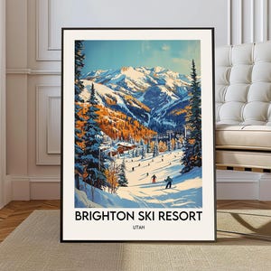 May include: A framed print of Brighton Ski Resort in Utah. The artwork depicts a vibrant winter landscape with skiers on a snowy slope, surrounded by snow-covered mountains and evergreen trees. The sky is a clear blue.