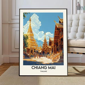 May include: A framed art print featuring a golden temple complex in Chiang Mai, Thailand. The artwork showcases ornate architecture, a vibrant blue sky, and fluffy white clouds. The text "CHIANG MAI THAILAND" is displayed at the bottom of the print.