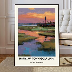 Può includere: Stampa artistica incorniciata di Harbour Town Golf Links a Hilton Head Island. L'opera raffigura un campo da golf con un faro sotto un cielo colorato al tramonto. La stampa è in una cornice nera.