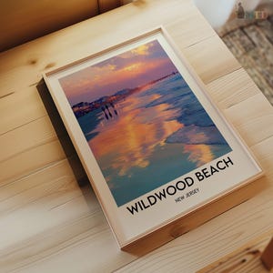 K&ouml;nnte beinhalten: Ein gerahmter Druck mit einer Strandszene bei Sonnenuntergang. Das Bild zeigt einen lebendigen Himmel mit orangefarbenen und violetten Farbt&ouml;nen, die sich im Wasser und im nassen Sand spiegeln. Der Text "Wildwood Beach, New Jersey" ist unten aufgedruckt.