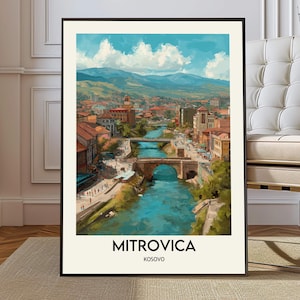 Puede incluir: Una impresión artística enmarcada de Mitrovica, Kosovo, con un río, puentes y edificios. La obra de arte presenta un colorido paisaje urbano con cielo azul y montañas. El nombre de la ciudad está impreso en negrita, en letras negras en la parte inferior.