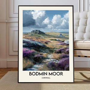 May include: A framed art print of Bodmin Moor, Cornwall. The landscape painting depicts a path winding through purple heather and grassy hills under a cloudy sky. The artwork is framed in black with the text "BODMIN MOOR" and "CORNWALL" at the bottom.