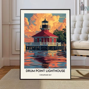 May include: A framed art print of Drum Point Lighthouse on Chesapeake Bay. The lighthouse has a red roof and white siding, set against a vibrant sunset sky. The water reflects the colorful sky and the lighthouse.