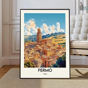 Puede incluir: Una impresión artística enmarcada de Fermo, Italia, con una ilustración detallada de los tejados de la ciudad, un campanario prominente y colinas onduladas bajo un cielo azul con nubes esponjosas. Las palabras "FERMO" e "ITALY" están impresas en la parte inferior.