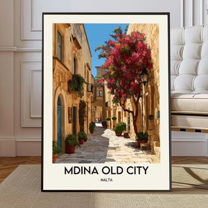 May include: Framed art print featuring a picturesque street scene in Mdina, Malta. The artwork depicts a narrow cobblestone street lined with sandstone buildings, vibrant red flowering trees, and potted plants. The text "MDINA OLD CITY MALTA" is at the bottom.