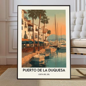 Può includere: Una stampa artistica incorniciata raffigurante una scena portuale con barche, edifici e palme. L'opera d'arte presenta una tavolozza di colori beige, blu e arancione. Il testo "PUERTO DE LA DUQUESA" e "COSTA DEL SOL" è visualizzato in basso.