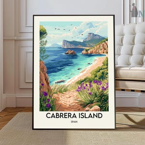 May include: A framed art print of Cabrera Island, Spain. The artwork depicts a coastal landscape with turquoise water, a sandy beach, and a path lined with purple flowers. The sky is blue with a few clouds and birds. The text "CABRERA ISLAND SPAIN" is at the bottom.