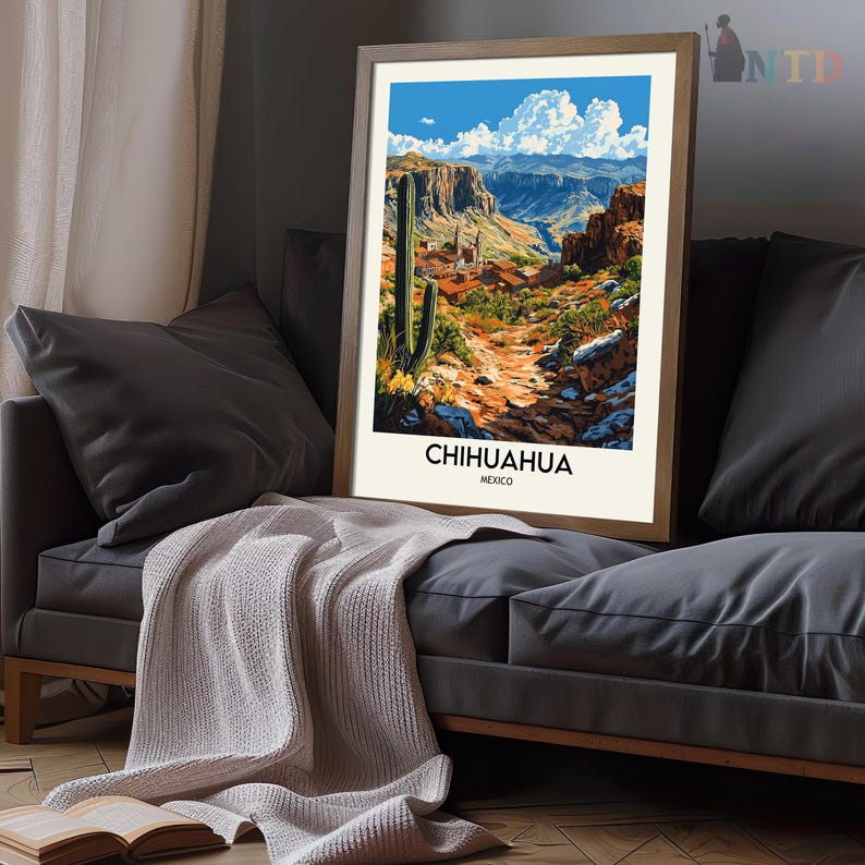 Peut inclure: Une affiche encadr&eacute;e repr&eacute;sentant un paysage de Chihuahua, au Mexique. L'&oelig;uvre d'art montre un paysage d&eacute;sertique avec un cactus imposant, un chemin sinueux et des montagnes sous un ciel bleu nuageux. L'affiche est pos&eacute;e sur un canap&eacute; gris.