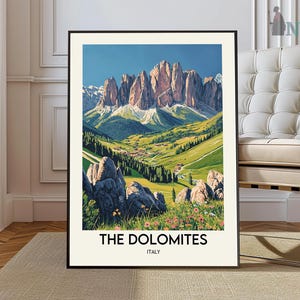 May include: A framed art print depicting the Dolomites in Italy. The image shows majestic mountains, green valleys, and a village under a bright blue sky. The text "THE DOLOMITES ITALY" is printed at the bottom of the artwork, which is framed in black.