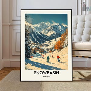 May include: A framed art print of a ski resort scene. The artwork depicts skiers on a snowy slope with a backdrop of snow-capped mountains under a blue sky. The print includes the text "SNOWBASIN SKI RESORT" at the bottom.