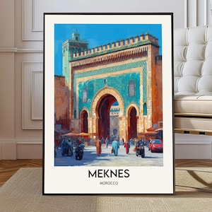 Puede incluir: Impresión artística enmarcada de Meknes, Marruecos. La obra representa un arco turquesa y dorado con una torre, sobre un cielo azul. Se ven personas y vehículos en primer plano. La palabra "MEKNES" está impresa en la parte inferior.