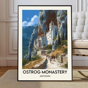 May include: A framed art print showing the Ostrog Monastery in Montenegro. The image features a white monastery built into a cliff face, with a path leading to it. The sky is blue with white clouds. The text "OSTROG MONASTERY MONTENEGRO" is at the bottom.