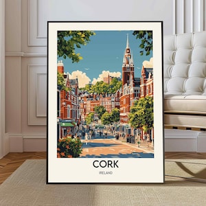 May include: A framed art print showing a street scene in Cork, Ireland. The illustration features buildings in red and orange, a tall church spire, and green trees. The word "CORK" is printed at the bottom of the artwork, with "IRELAND" below.