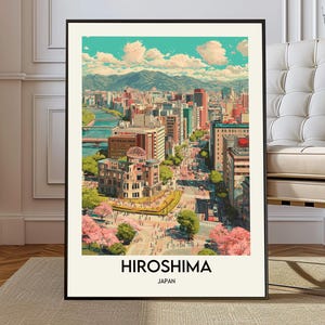 Puede incluir: Una impresión artística enmarcada de Hiroshima, Japón, con un colorido paisaje urbano con edificios, un río y montañas al fondo. La impresión tiene las palabras "HIROSHIMA" y "JAPAN" en negro en la parte inferior.