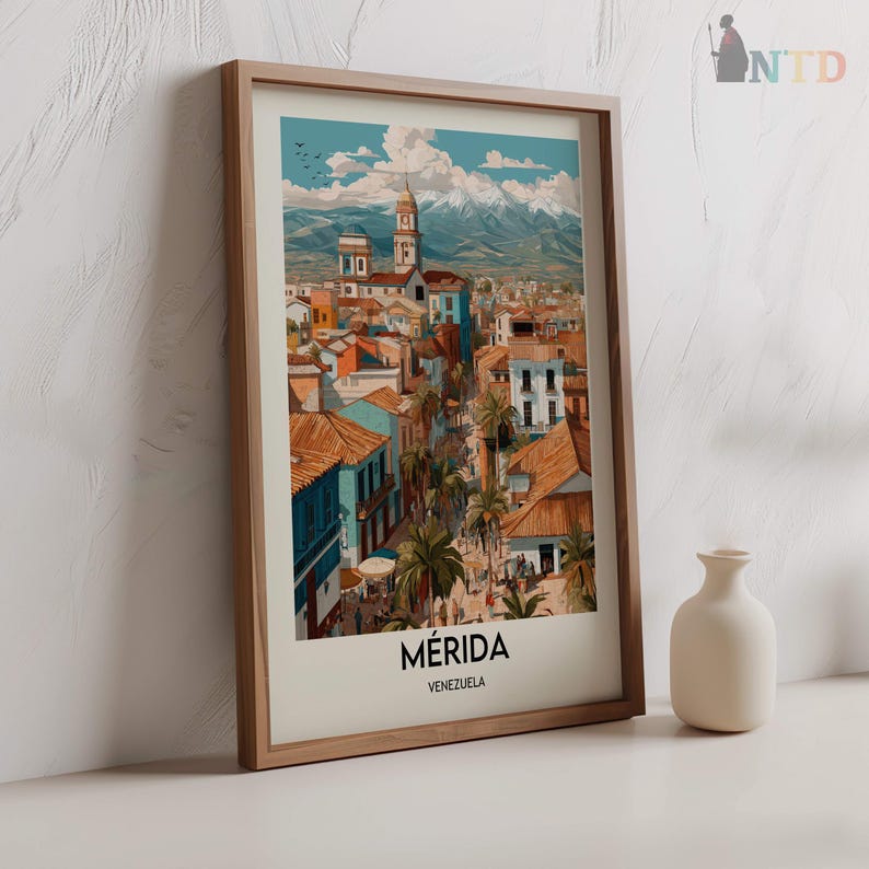 K&ouml;nnte beinhalten: Ein gerahmter Kunstdruck von M&eacute;rida, Venezuela, mit einer farbenfrohen Stadtlandschaft mit Geb&auml;uden, Palmen und Bergen im Hintergrund. Der Druck befindet sich in einem Holzrahmen und tr&auml;gt unten den Namen der Stadt.
