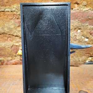 Pu&ograve; includere: Un vassoio rettangolare nero con una superficie strutturata. Il vassoio &egrave; realizzato in un materiale scuro e ha un design semplice e moderno. Il vassoio &egrave; appoggiato su una superficie di legno.