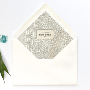 May include: A white envelope with a map of New York City on the front. The map is in black and white and includes the text "City of New York 1918". A green stamp with a picture of the Brooklyn Bridge is on the envelope.