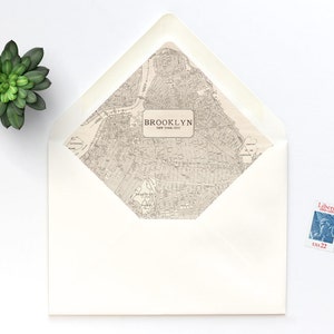 May include: A white envelope with a map of Brooklyn, New York City on the front. The map is in black and white and includes the text "BROOKLYN NEW YORK CITY". A blue postage stamp with the text "Liberty" is on the upper right corner of the envelope.