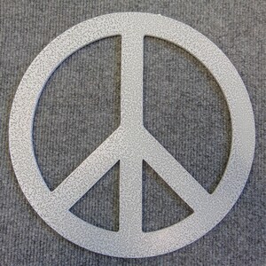 May include: A silver-colored peace sign with a textured surface. The peace symbol is a circle with a vertical line in the center and two diagonal lines extending downwards. The symbol is a popular emblem of peace and non-violence.