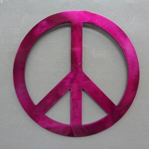 May include: A vibrant, fuchsia-colored peace sign. The symbol is a circle with a vertical line through the center and two diagonal lines extending downwards. The sign is set against a gray background.