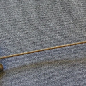 May include: A vintage brass lamp arm featuring a long, slender rod connected to a decorative ceiling canopy at one end and a multi-socket light fixture at the other. The metal shows signs of age with a tarnished, weathered patina throughout.