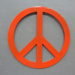 May include: Bright orange peace symbol. The symbol is a circle with a vertical line in the center and two diagonal lines extending downward. The symbol is set against a gray background.