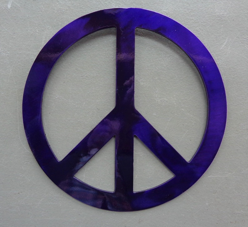 May include: A vibrant, deep purple peace sign. The symbol is a circle with a vertical line and two diagonal lines inside. The color has a marbled effect, with lighter shades of purple throughout. The background is a light gray.