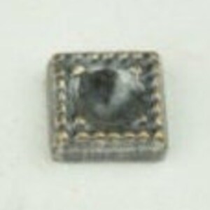 May include: A small, square, clear glass tile with a rope-like border. The tile is slightly cloudy and has a gray tint.