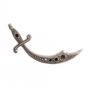 May include: A silver-toned metal pendant in the shape of a scimitar, a curved sword with a decorative handle.