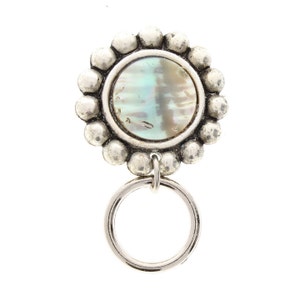May include: A silver-toned pendant with a round, iridescent mother-of-pearl inlay surrounded by a circle of small beads. The pendant hangs from a silver ring.