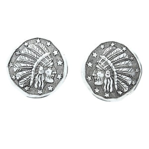 May include: A pair of silver-toned earrings featuring a Native American chief profile with a feathered headdress. The earrings are circular and have a textured surface.