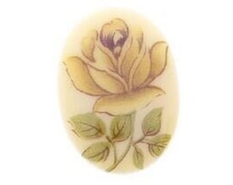 May include: A cream-colored oval-shaped cabochon with a yellow rose painted on it.
